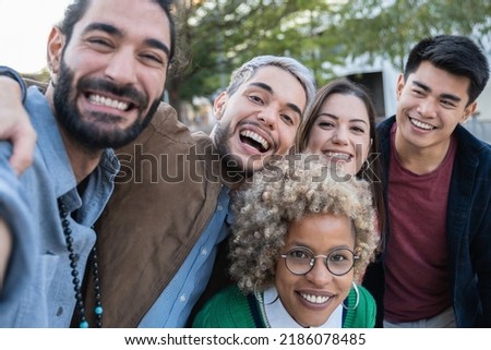 Multiracial happy friends having fun taking selfie outdoor - Focus on center man face