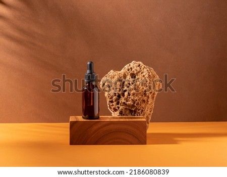 Cosmetic dropper bottle on creative modern podium, wood stone. Brown background with hard shadows