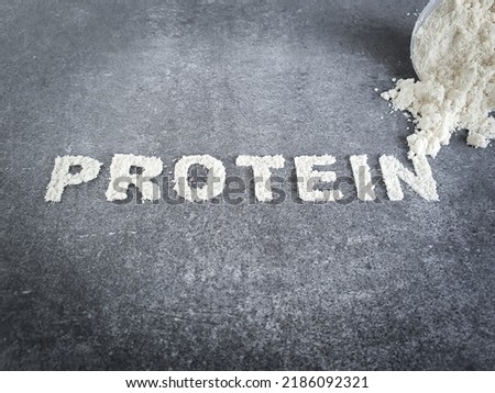 Measuring plastic scoop of whey protein isolate powder and powder text in letterpress on stone background representin sport dietary food nutrition and supplementation for muscle gain Royalty-Free Stock Photo #2186092321