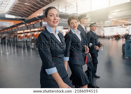 Two flight attendants and pilots walking through the terminal to the plane Royalty-Free Stock Photo #2186094515