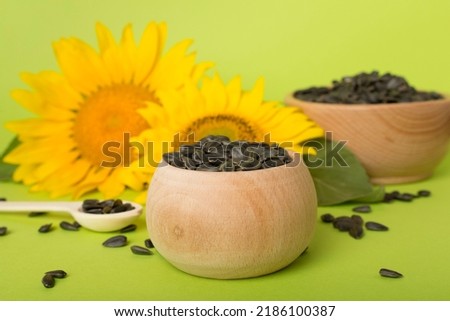 Sunflower seeds and flowers on color background.
