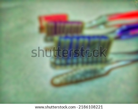 Defocussed abstract background Blue, purple and pink toothbrushes line up against a white background at night, Indonesia.