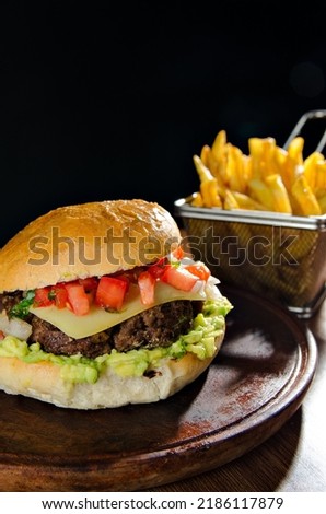 the photograph shows a delicious hamburger accompanied by french fries