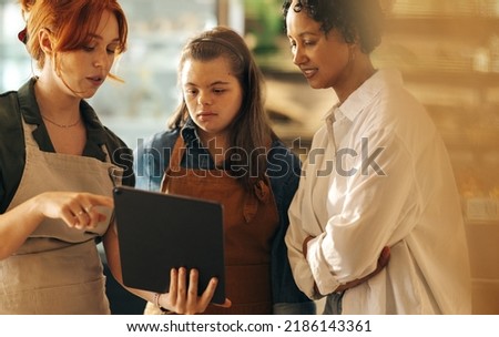 Supermarket manager using a digital tablet while having a discussion with her employees in a staff meeting. Group of diverse women working together in an all-female small business. Royalty-Free Stock Photo #2186143361