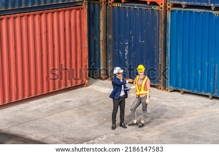 Professional two engineer container cargo foreman in helmets working standing and using walkie talkie checking stock into container for loading.logistic transport and business industry export