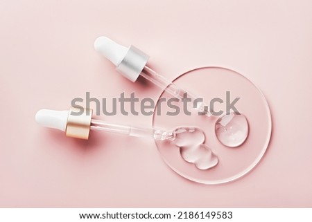 Two pipettes with different samples of gels cosmetic products in petri dish on pink background Royalty-Free Stock Photo #2186149583