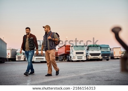 Professional truck drivers talking while walking on parking lot. Copy space. Royalty-Free Stock Photo #2186156313