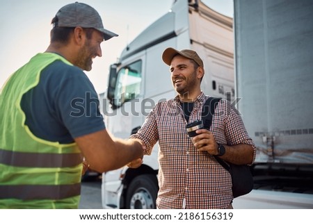 Young happy truck driver shaking hands with a dispatcher on parking lot. Royalty-Free Stock Photo #2186156319
