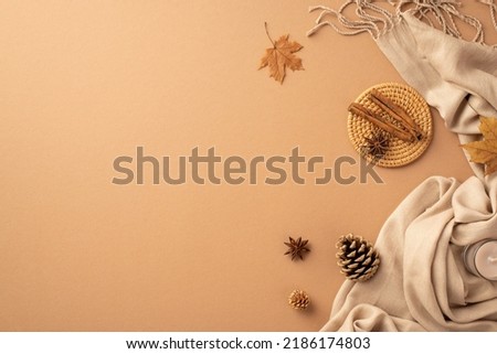 Autumn mood concept. Top view photo of cinnamon sticks anise on rattan serving mat yellow maple leaves candle pine cones and plaid on isolated beige background with empty space Royalty-Free Stock Photo #2186174803
