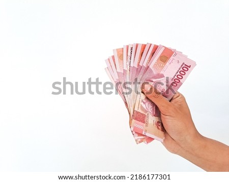 Man's Hand holding rupiah money isolates on white background Royalty-Free Stock Photo #2186177301