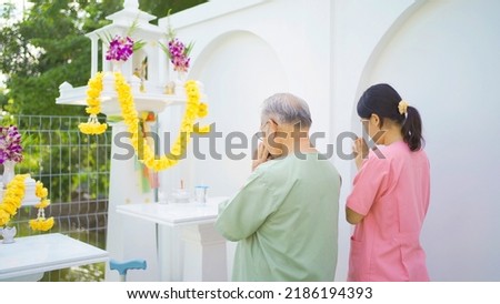 Old elderly Asian patient or pensioner and a nurse pay respect to Buddha in nursing home in garden park. Senior lifestyle activity recreation. Retirement. Health care physical therapy. Royalty-Free Stock Photo #2186194393
