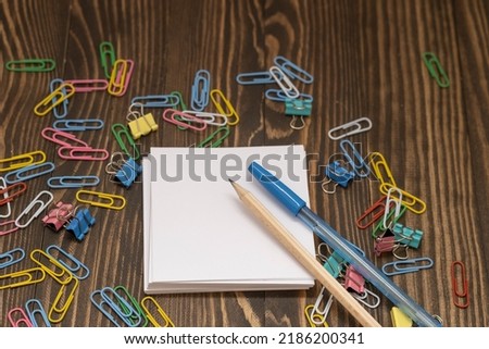stationery colored paper clips around a mocap record sheet on a wooden background, the concept is coming to school soon