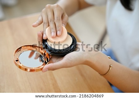 A young female or make-up artist holding a compact powder, using pressed powder, doing make-up for her daily routine. cropped and close-up image Royalty-Free Stock Photo #2186204869