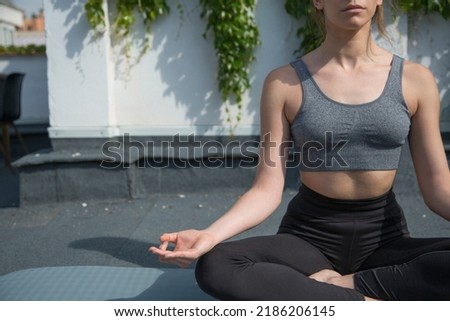 Cropped photo of an unrecognizable fit woman doing the lotus yoga pose in a terrace with plants