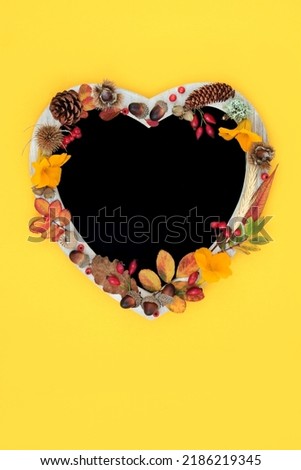 Heart shaped Autumn chalkboard frame, leaves, flowers, berries, grain and nuts. Thanksgiving and Halloween vivid nature composition with natural flora. On yellow background. Flat lay.