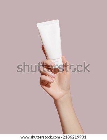 Hand holding blank white plastic tube on pink background. Cosmetic beauty product branding mockup. Copy space. High quality photo Royalty-Free Stock Photo #2186219931