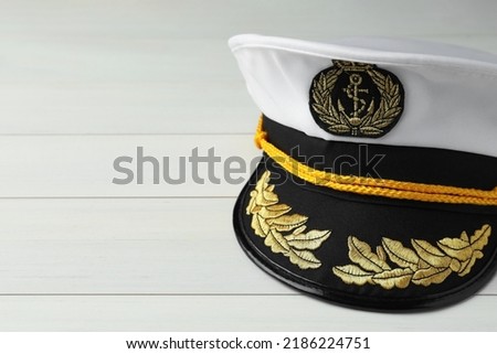 Peaked cap with accessories on white wooden background, closeup. Space for text