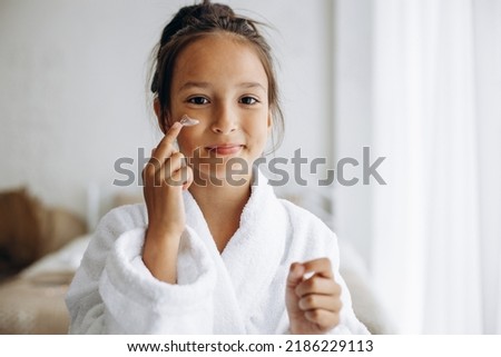 Cute girl applying face cream