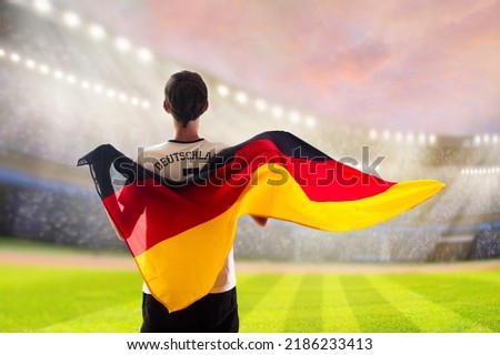 Germany football supporter on stadium. German fans on soccer pitch watching team play. Group of supporters with flag and national jersey cheering for Germany. Championship game.  Royalty-Free Stock Photo #2186233413