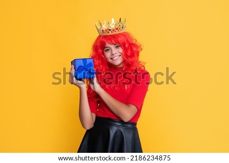 child smile in crown with present box on yellow background
