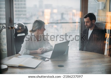 A disgruntled boss scolds a subordinate in her office at the table. The female director is dissatisfied with the work of the male employee; they sit at the table and discuss the problem.