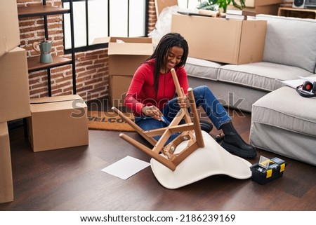 African american woman smiling confident repair chair at new home