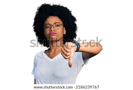 Young african american woman wearing casual white t shirt looking unhappy and angry showing rejection and negative with thumbs down gesture. bad expression. 
