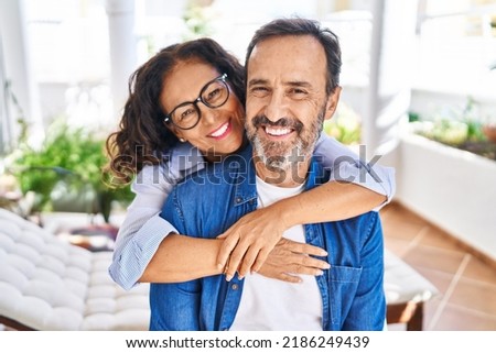 Middle age hispanic couple smiling confident hugging each other sitting on hammock at terrace Royalty-Free Stock Photo #2186249439