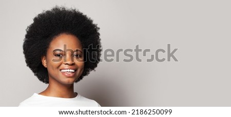 Portrait of happy woman with curly hair against white studio wall banner background