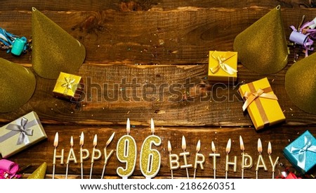 golden letters of the candle with the number happy birthday, the background of the gift boxes with candles happy birthday on the background of brown boards. Copy spacePostcard Happy birthday 96