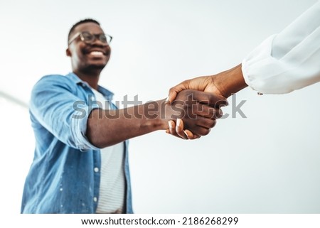 Happy multiethnic businesspeople shake hands close deal make agreement at meeting in office. Smiling African American handshake excited female client, get acquainted at briefing.