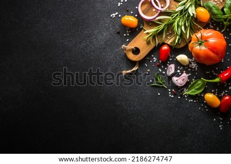 Food cooking background on black stone table. Fresh vegetables, herbs and spices. Top view with copy space. Royalty-Free Stock Photo #2186274747