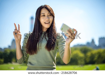 Young Asian Woman in a park taking a selfie picture photo