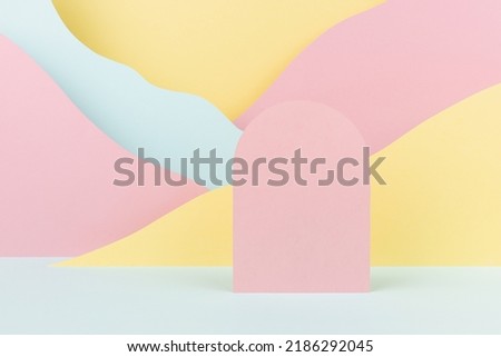 Arch pink podium mockup with abstract mountain landscape - colorful pastel pink, yellow, mint color slopes in baby cartoon naive style. Template for presentation of cosmetic, advertising, showing. 
