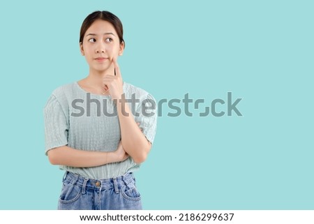 Pretty young Asian girl thinking and looking upwards. The concept of content thinks about future isolated on mint green background.