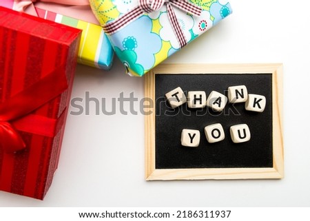 Top view of wooden cubes with thank you inscription on blackboard and gift box with ribbon.