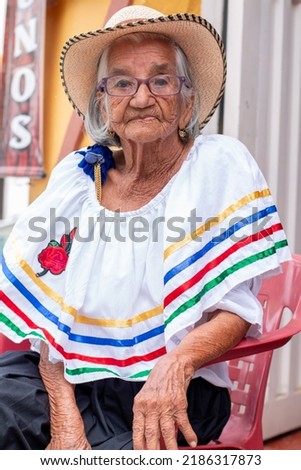 Portrait of a 95 year old woman dressed in a sombrero and typical Colombian costume. Royalty-Free Stock Photo #2186317873