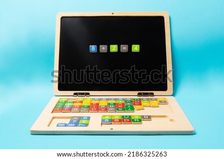 Educational wooden kid laptop with magnetic letters and numbers for learning. Mathematic equation  made of small colorfull numbers.
