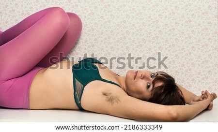 hairy woman with beautiful female armpits with hair. Woman lying with arms raised showing unshaven hairy armpits. Body positive, feminism and hairy woman concept.