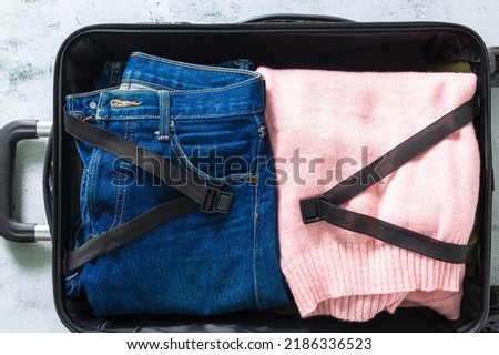 Jeans and clothes in luggage,jeans in suitcase top view,Packing suitcases. Shot of Clothes and jeans in baggage