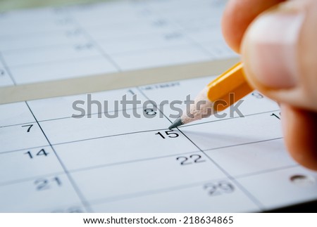 Person marking the date of the 15th with a pencil on a blank calendar with date squares as a reminder of an important day or to schedule a meeting or event Royalty-Free Stock Photo #218634865
