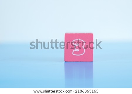 Number 3 written on colorful wooden block placing on blue background. 