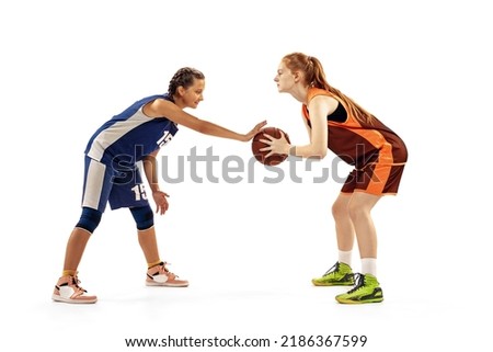 Two basketball players, young girls, teen playing basketball isolated on white background. Concept of sport, team, enegry, competition, skills. Training, junior game. Copy space for ad, text