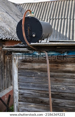 an old heating tank stands on the roof of a summer shower in the village. High quality photo