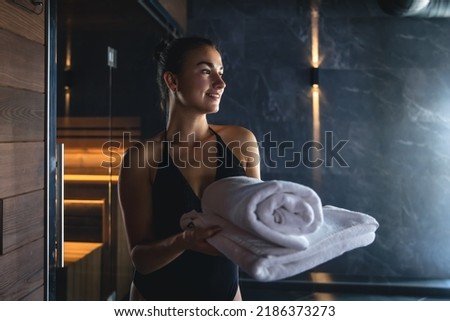 Attractive young woman with towels is relaxing in the sauna. Royalty-Free Stock Photo #2186373273