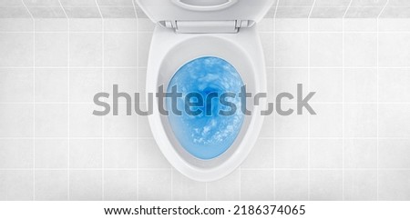 Top view of toilet bowl, blue detergent flushing in it Royalty-Free Stock Photo #2186374065