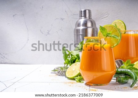  Carrot Ginger Margarita cocktail with lime, mint and hot chili pepper, original vegetable spicy drink on white tiled background copy space