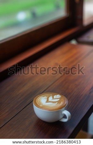 Hot coffee latte art in a cup 
on wooden bar