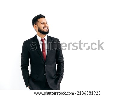 Copy-space for your presentation. Friendly elegant influential arabian or indian man in formal suit, standing over isolated white background, looking away, thinking, planning, dreaming, smiles Royalty-Free Stock Photo #2186381923