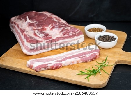 Cured ham with pepper and salt on wooden table